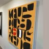 Large-scale yellow modernist abstract painting with crisp black-and-white shapes, shown at an angle to reveal the painting’s edges and depth.