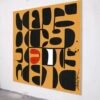 Yellow modernist abstract painting with crisp black geometric shapes displayed on a gallery wall, viewed from an angle. angle.