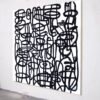 Robert R – Black and White Abstract Painting, Full Angled View Full view of a black-and-white modern abstract painting with bold street-art-inspired linework, displayed at an angle on a gallery wall.