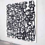 Full view of a black-and-white modern abstract painting with bold street-art-inspired linework, displayed at an angle on a gallery wall.