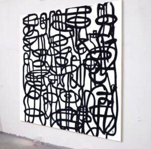 Full view of a black-and-white modern abstract painting with bold street-art-inspired linework, displayed at an angle on a gallery wall.
